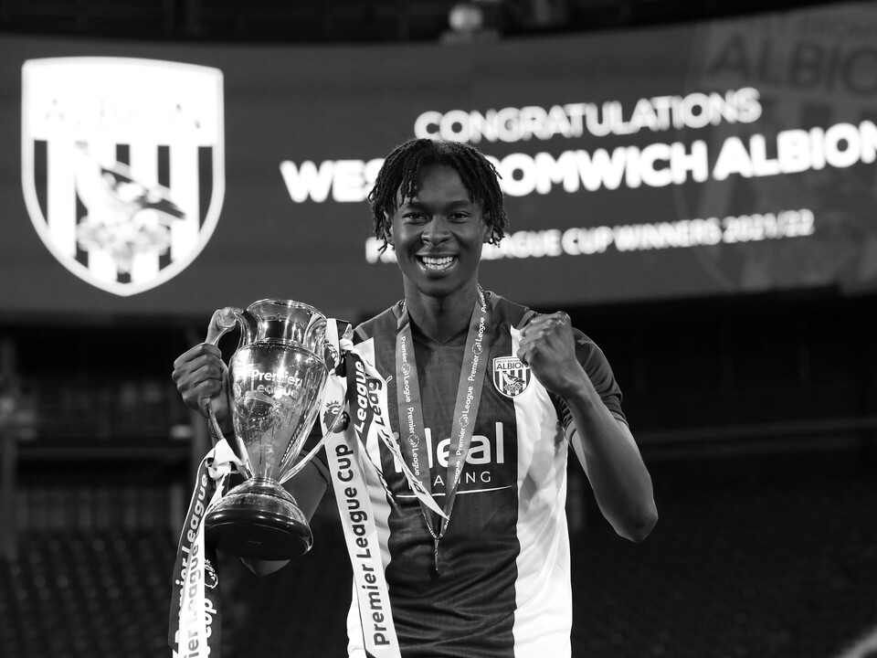 Quevin Castro smiling at the camera while holding up the PL Cup trophy 