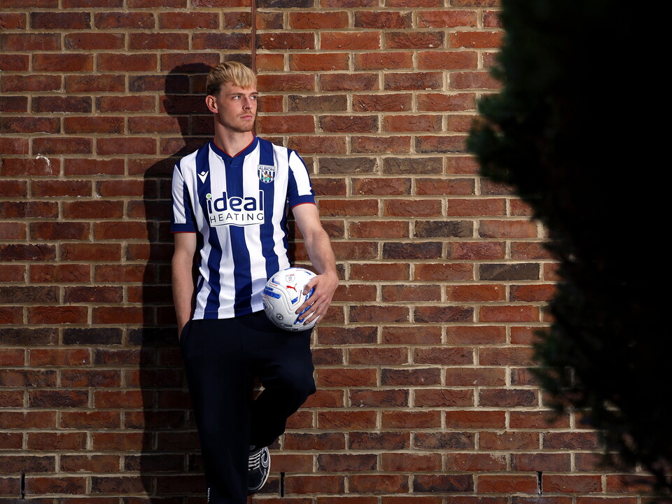 An image of Toby Collyer leaning up against a wall in an Albion shirt