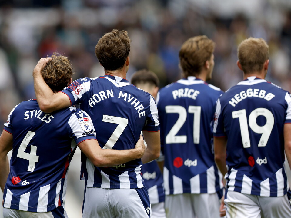 Callum Styles and Felix Horn Myhre facing away from camera celebrating a goal in the home kit against QPR 