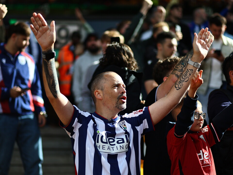 A WBA fan cheering during a game with his arms in the air