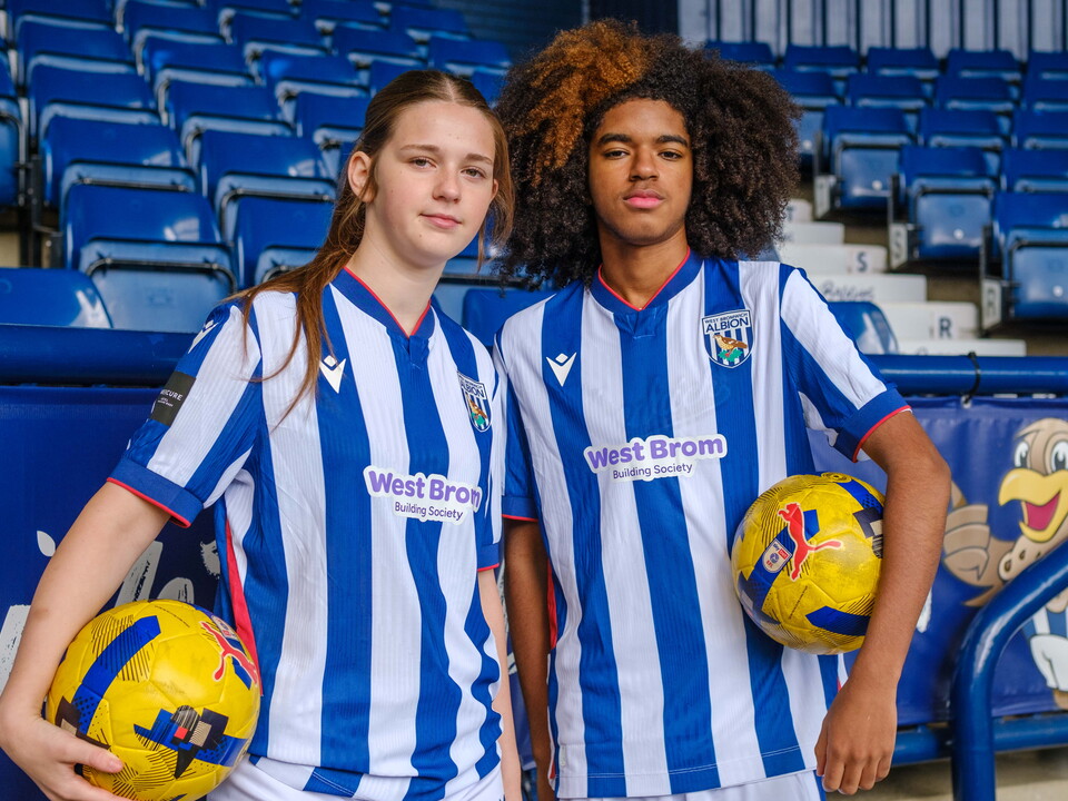 Two Post-16 players standing on the East stand holding a football