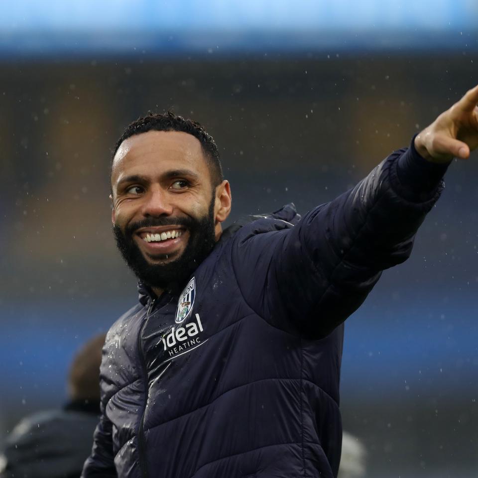 Kyle Bartley smiling and pointing while wearing an Albion coat